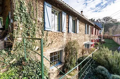 a brick building with windows and ivy on it at La Rustique, maison de charme proche Carcassonne - jardin, wifi, tout équipée in Cuxac-Cabardès