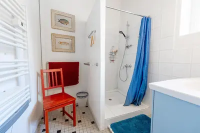 a bathroom with a shower and a red chair at La Rustique, maison de charme proche Carcassonne - jardin, wifi, tout équipée in Cuxac-Cabardès