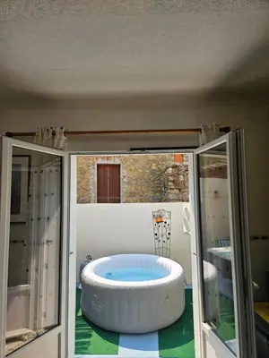 a large bath tub in a room with glass doors at Serge Le Belge - Sejour authentique chez l habitant a Lezignan Corbieres in Lézignan-Corbières