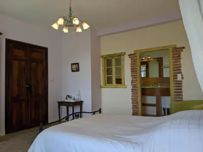 a bedroom with a white bed and a wooden door at La Caminada Vielha in Montaillou