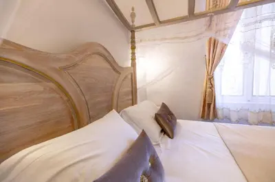 a bed with a wooden head board and a window at Chambre a Baldaquin Maison de L'Église Du couvent in Narbonne