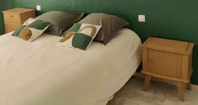 a white bed with pillows and a green wall at LE CELESTHYM - SPA Privatif in Conques-sur-Orbiel
