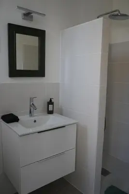 a white bathroom with a sink and a mirror at LE CELESTHYM - SPA Privatif in Conques-sur-Orbiel