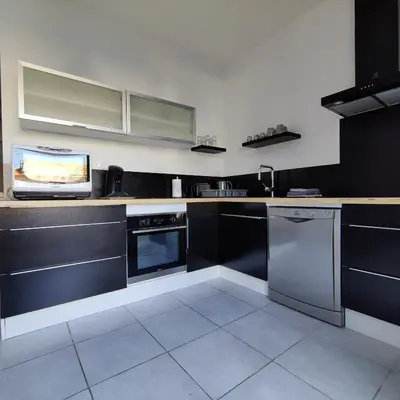 a kitchen with black cabinets and a tv on the counter at LE CELESTHYM - SPA Privatif in Conques-sur-Orbiel