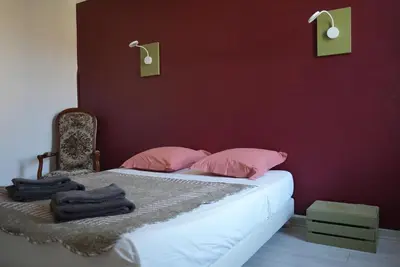 a bed with pink pillows and a red wall at LE CELESTHYM - SPA Privatif in Conques-sur-Orbiel
