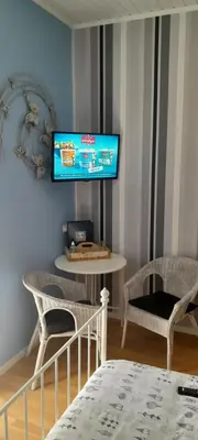 a room with a tv on a wall with two chairs at Sur la Bonnefooi in Prades-sur-Vernazobre