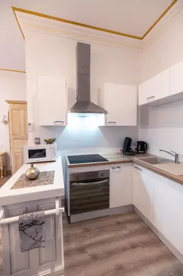 a kitchen with white cabinets and a stove top oven at Studio du Maire Maison de L'Église du Couvent in Narbonne