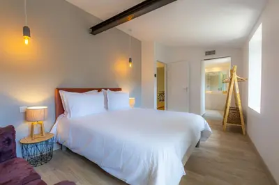a bedroom with a large white bed and a chair at Les Pimprenelles in Carcassonne