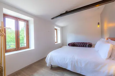 a white bedroom with a bed and a window at Les Pimprenelles in Carcassonne