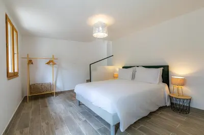 a bedroom with a large white bed and a lamp at Les Pimprenelles in Carcassonne