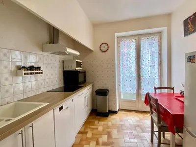 a kitchen with white cabinets and a table and a window at Appartement Cité de Carcassonne in Carcassonne