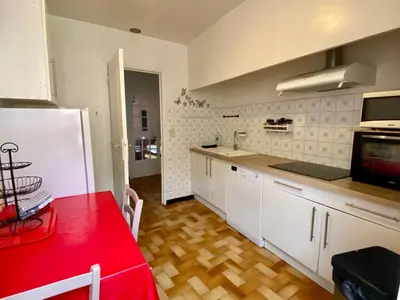 a kitchen with white cabinets and a red table at Appartement Cité de Carcassonne in Carcassonne