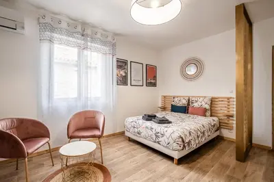a bedroom with a bed and two chairs at Studio Marceau Clim Wifi Centre ville 2 pers in Lézignan-Corbières