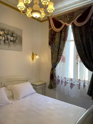 a bedroom with a bed and a chandelier and a window at Appartement Maison de L'Église du Couvent in Narbonne