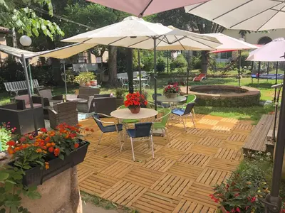 a patio with tables and chairs and umbrellas at La Vie en Roses in Rennes-les-Bains