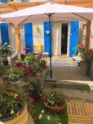 an umbrella in a garden with flowers and plants at La Vie en Roses in Rennes-les-Bains