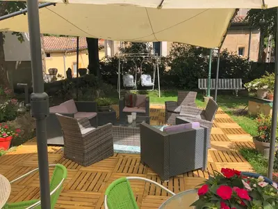 a patio with chairs and an umbrella on a wooden deck at La Vie en Roses in Rennes-les-Bains