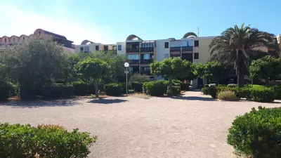 a large building with a lot of trees and bushes at Studio cabine avec jardinet à 30 m de la plage, au calme. in Gruissan