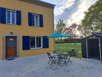 a house with a table and chairs and an umbrella at Gîte La Dolce Vita in Saint-Félix-Lauragais
