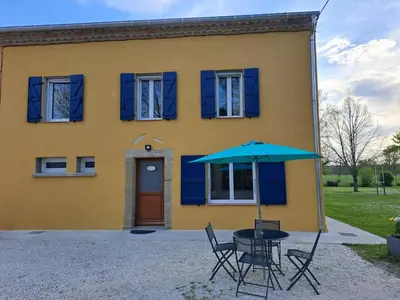 a house with a table and chairs and an umbrella at Gîte La Dolce Vita in Saint-Félix-Lauragais