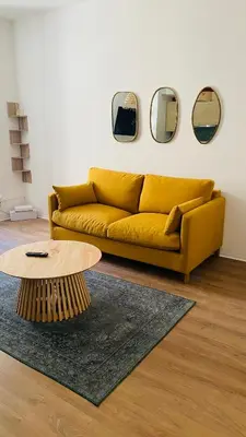 a yellow couch in a living room with three mirrors at Le Bout du Monde Appartement Hyper-centre in Carcassonne