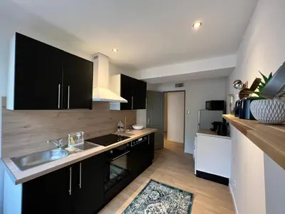 a kitchen with black cabinets and a sink at Le Rêve Bleu Appartement Hyper-centre in Carcassonne