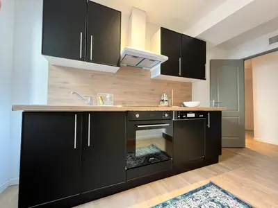 a kitchen with black cabinets and a stove at Le Rêve Bleu Appartement Hyper-centre in Carcassonne