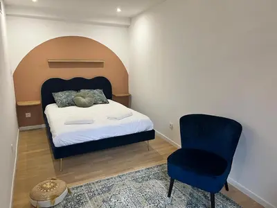 a bedroom with a bed and a blue chair at Le Rêve Bleu Appartement Hyper-centre in Carcassonne