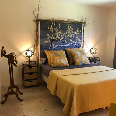a bedroom with a bed with a painting on the wall at Le Nid des Corbières in Bizanet