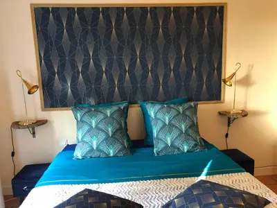 a bedroom with a blue bed with a large headboard at Le Nid des Corbières in Bizanet