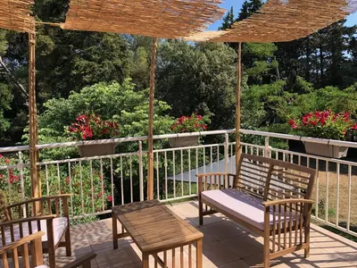 a porch with a swing and chairs and flowers at Le Nid des Corbières in Bizanet