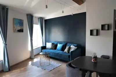 a living room with a blue couch and a table at A l'ombre des remparts in Carcassonne
