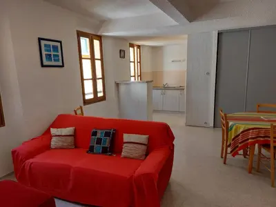 a living room with a red couch and a table at Gîte communal presbytère in Pézilla-de-Conflent