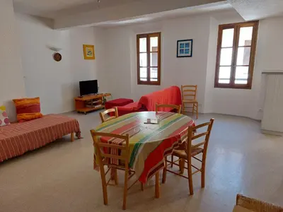 a living room with a table and chairs and a couch at Gîte communal presbytère in Pézilla-de-Conflent