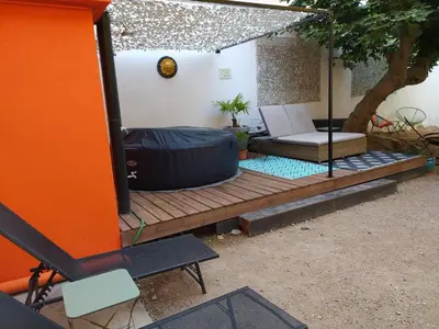 a room with a bed and a chair on a wooden deck at Le 9 de Cour, Chambre Kiwi in Carcassonne