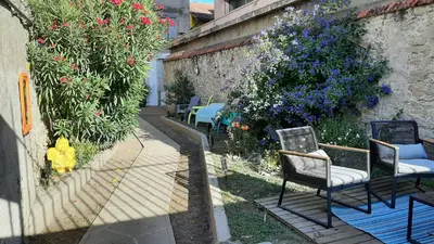 a patio with chairs and flowers next to a wall at Le 9 de Cour, Chambre Kiwi in Carcassonne