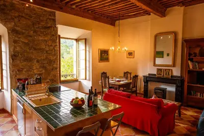 a living room with a red couch and a table at The Riverside Gîte Lagrasse in Lagrasse