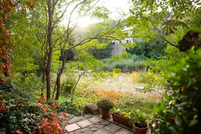 a garden with flowers and trees and a pathway at The Riverside Gîte Lagrasse in Lagrasse