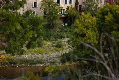 a garden with flowers and trees in front of a building at The Riverside Gîte Lagrasse in Lagrasse