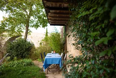 a table with a blue table cloth sitting in a yard at The Riverside Gîte Lagrasse in Lagrasse