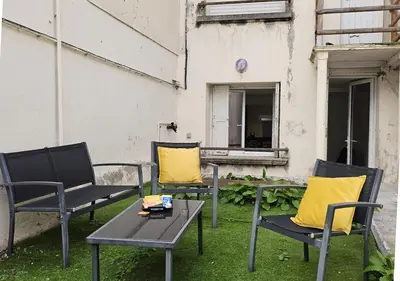 three chairs and a table with yellow pillows on a yard at Castelnaudary - Appartement JARDIN in Castelnaudary