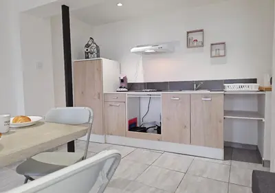 a kitchen with wooden cabinets and a table with chairs at Castelnaudary - Appartement JARDIN in Castelnaudary