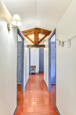 a hallway with open doors and a red tile floor at L'Escapade - Parking Gratuit - WIFI - Climatisation - Proche Cité - Tout Equipée in Carcassonne