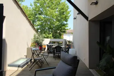a patio with chairs and tables on a deck at La villa du chai in Lézignan-Corbières