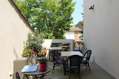 a patio with tables and chairs on a deck at La villa du chai in Lézignan-Corbières