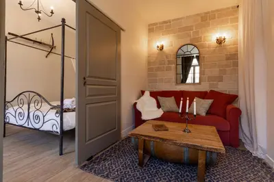 a living room with a red couch and a bed at Le Secret de la Taverne - Netflix/Wifi - Chasse Aux Trésor à l'intérieur in Carcassonne