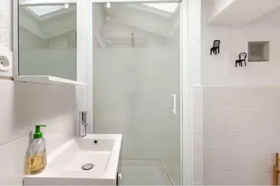 a white bathroom with a sink and a shower at Appartement 