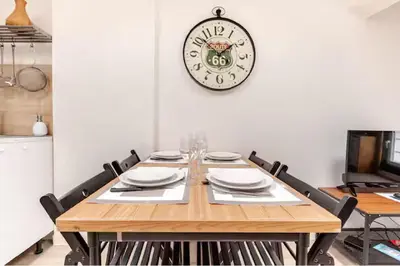 a dining room table with a clock on the wall at Appartement 