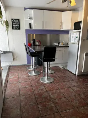 a kitchen with a table and chairs and a refrigerator at APPARTEMENT SUR LE PORT DE Gruissan in Gruissan