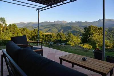 a couch and a table on a patio with mountains at The Restoration Place Pyrenees in Roquefixade